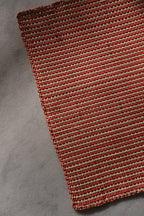 Iraca placemat with red and natural palm leaf design from Guanabana, showcasing vibrant colors and intricate pattern.