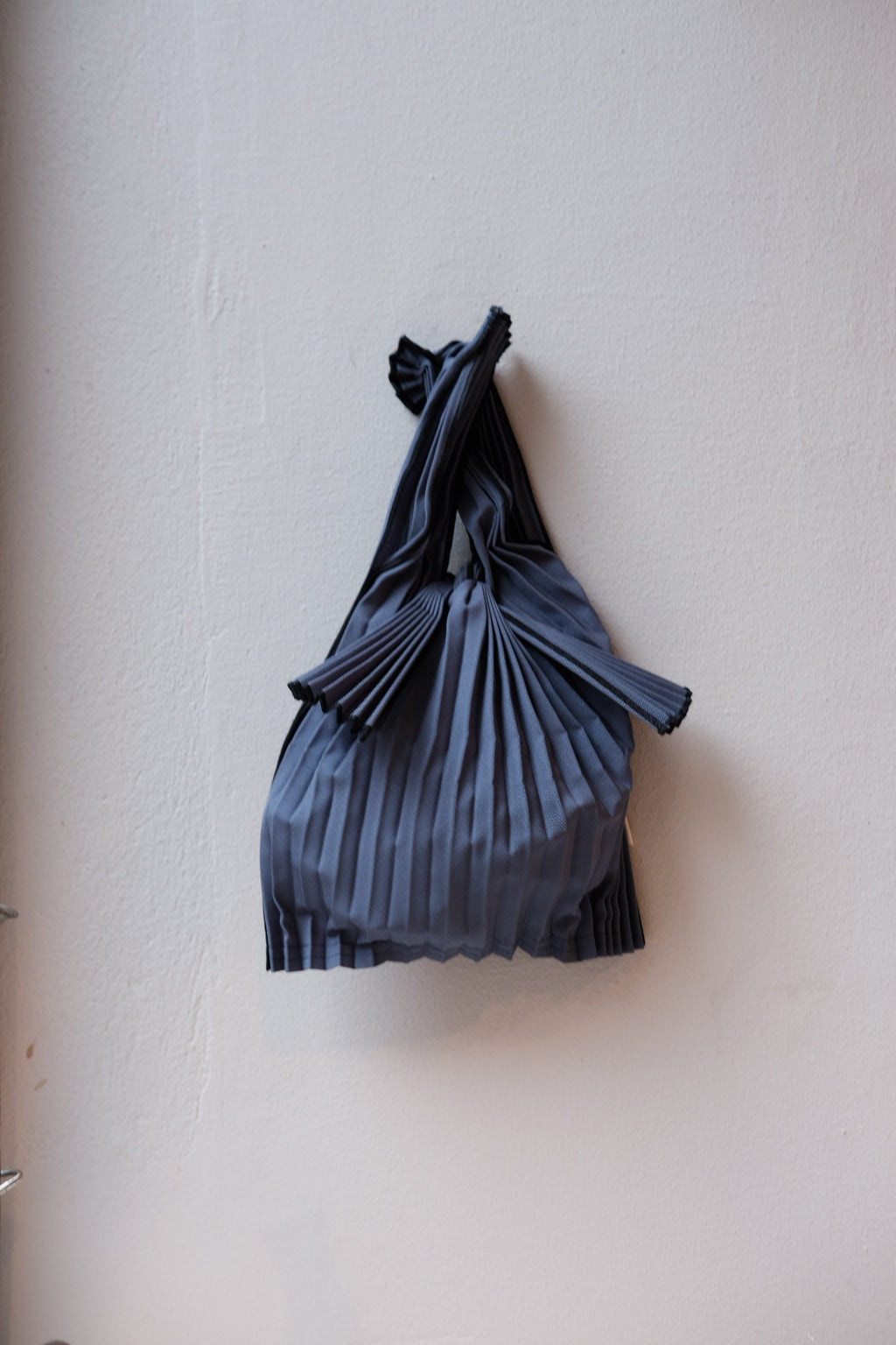 Mini mørkeblå plisseret taske fra Pleco, biologisk nedbrydelig og miljøvenlig, med elegant design.