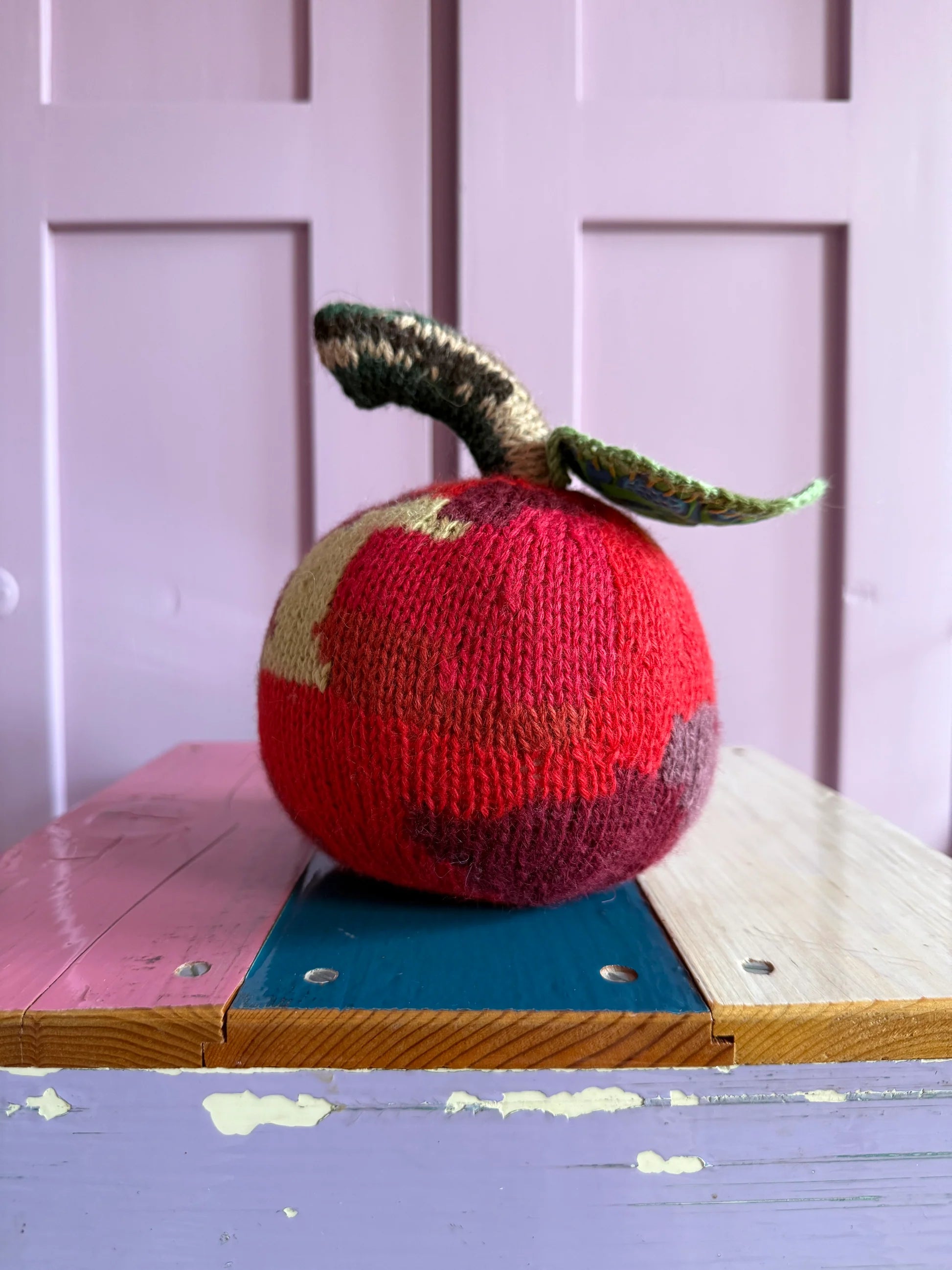 Hæklet æblepude by Creme de la Creme de la Helle, soft knitted cushion with apple design, perfect for cozy home decor.
