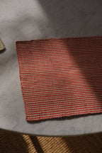Guanabana Iraca placemat with red and natural palm leaf patterns, showcasing woven design and vibrant colors.