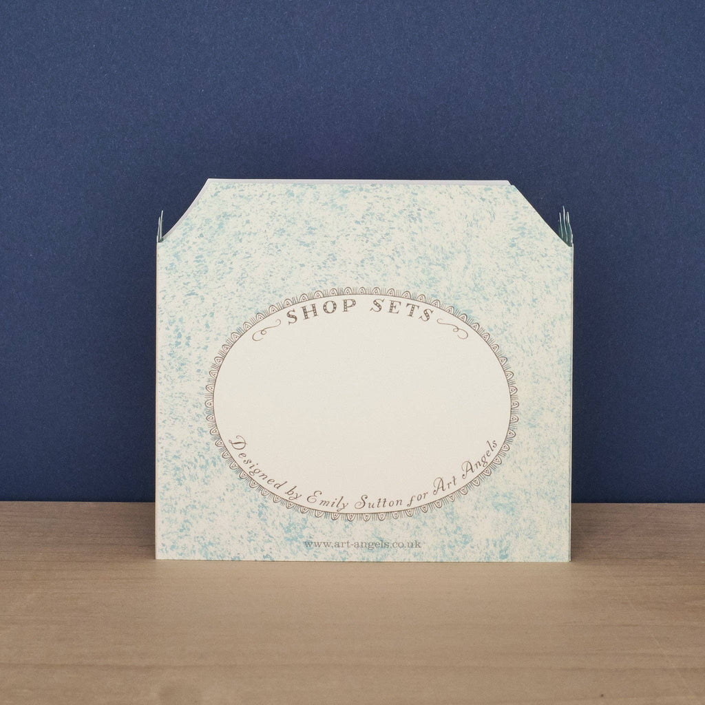 Art Angels Kort featuring a vibrant green grocer illustration with fresh produce and a charming market scene.