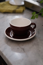 Brun kop og underkop fra ACME Classic Medium, keramisk kop med matchende underkop, perfekt til te eller kaffe.