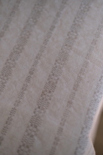 Hørdug i taupe med broderi, 140 x 250 cm, Linge Particulier, vises foran en spisebord.