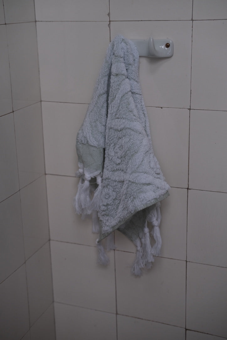 Green DORA hand towel, 50x30 cm, soft fabric with neatly hemmed edges, displayed folded on a white background.