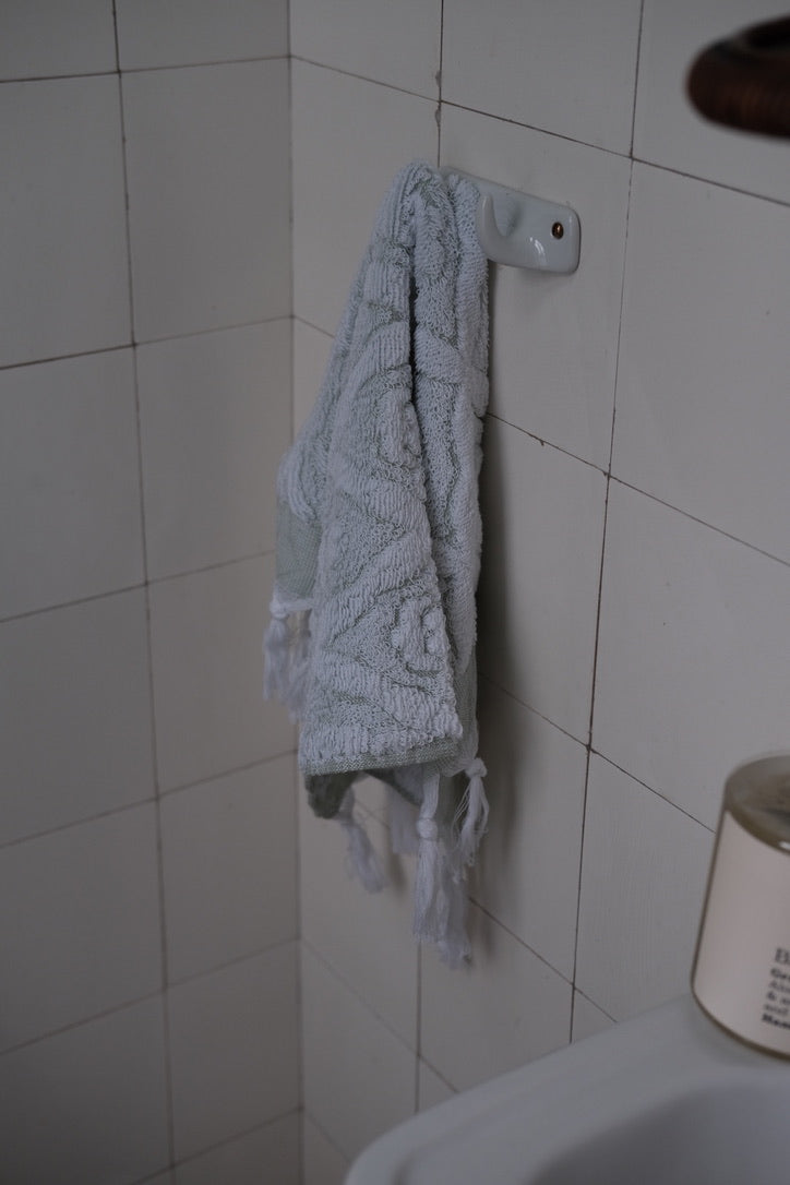 Green DORA hand towel, 50x30 cm, soft fabric with a textured pattern, suitable for bathroom or kitchen use.