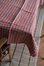 Hørdug fra Linge Particulier i Vichy Orange Ficelle med orange tern, 140 x 250 cm, vises fladt på et bord.