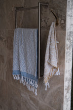 Blue DORA hand towel measuring 140x70 cm, soft and absorbent, displayed folded with textured fabric visible.