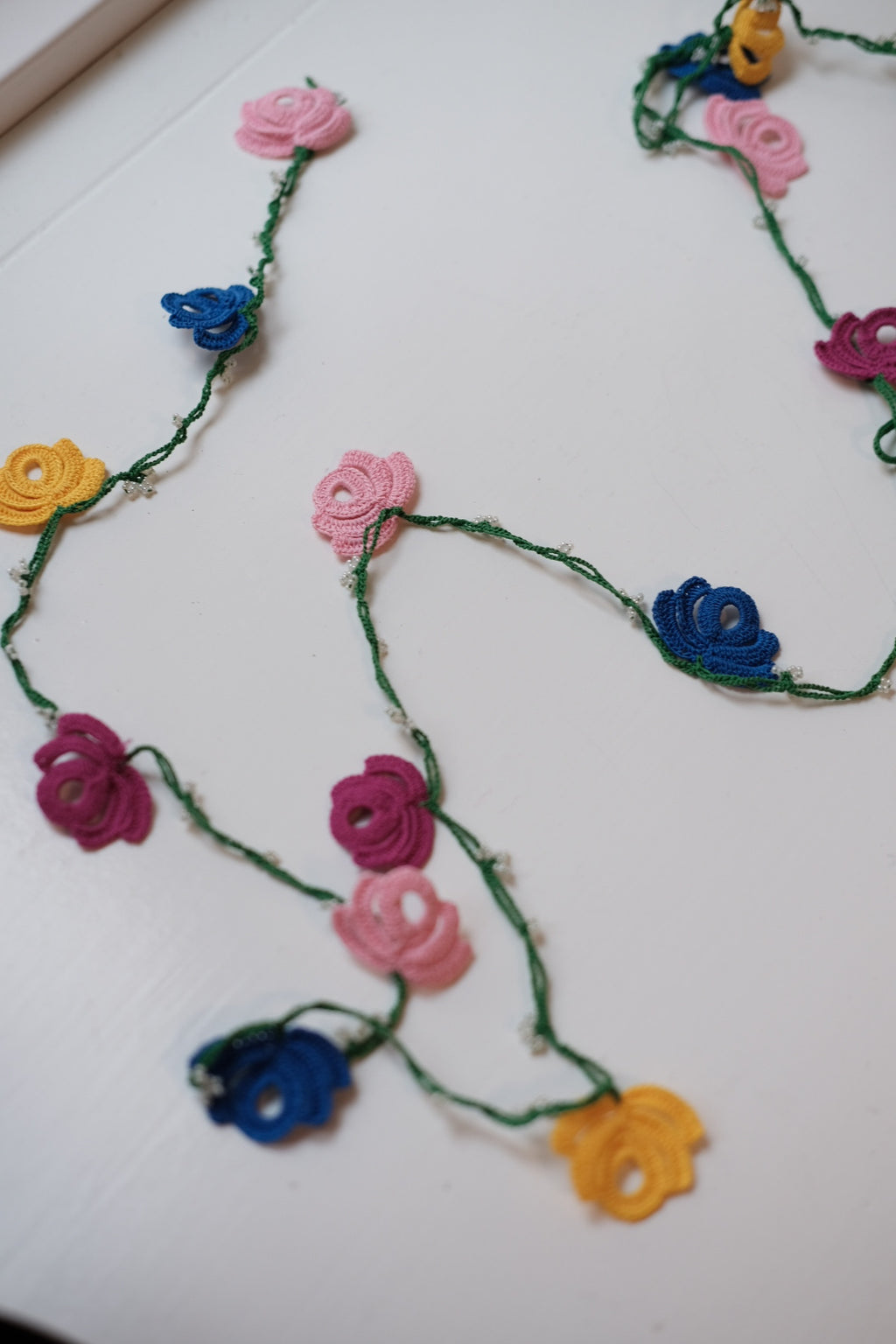 Green flower garland by Østerland, featuring vibrant blooms and a delicate design for festive decor.