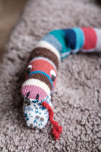 Cream-colored knitted snake-shaped rangle pillow by Creme de la Creme de la Helle, featuring a soft, textured knit design.