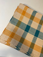 Guanabana Dækkeserviet with orange and blue plaid Iraca Palmeblade design, vibrant fabric table cover with tropical pattern.