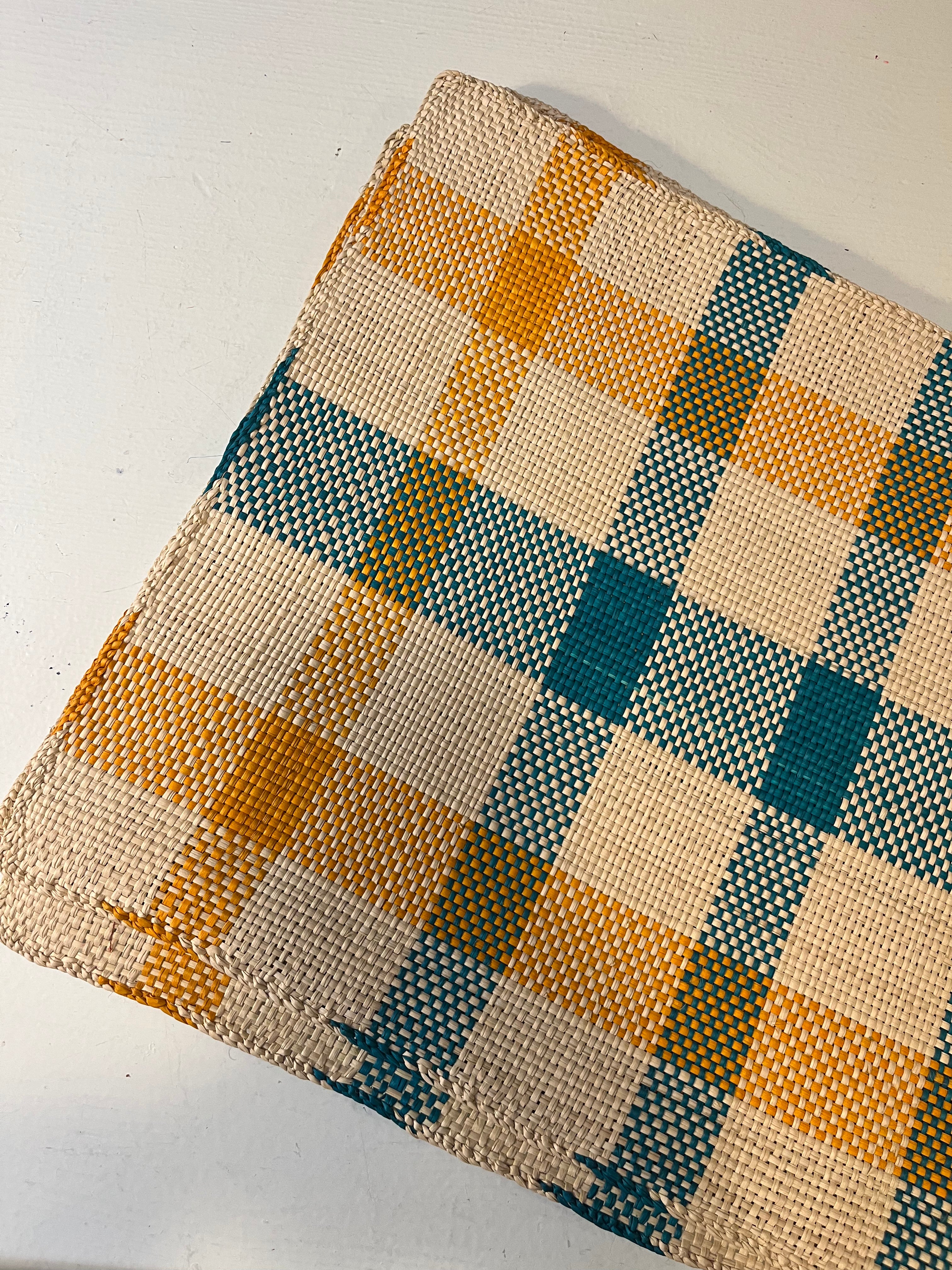 Guanabana Dækkeserviet with orange and blue plaid Iraca Palmeblade design, vibrant fabric table cover with tropical pattern.