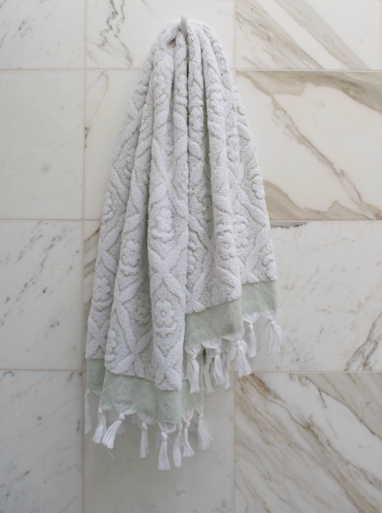 Green DORA hand towel, 140x70 cm, soft cotton fabric, shown folded on a wooden surface.