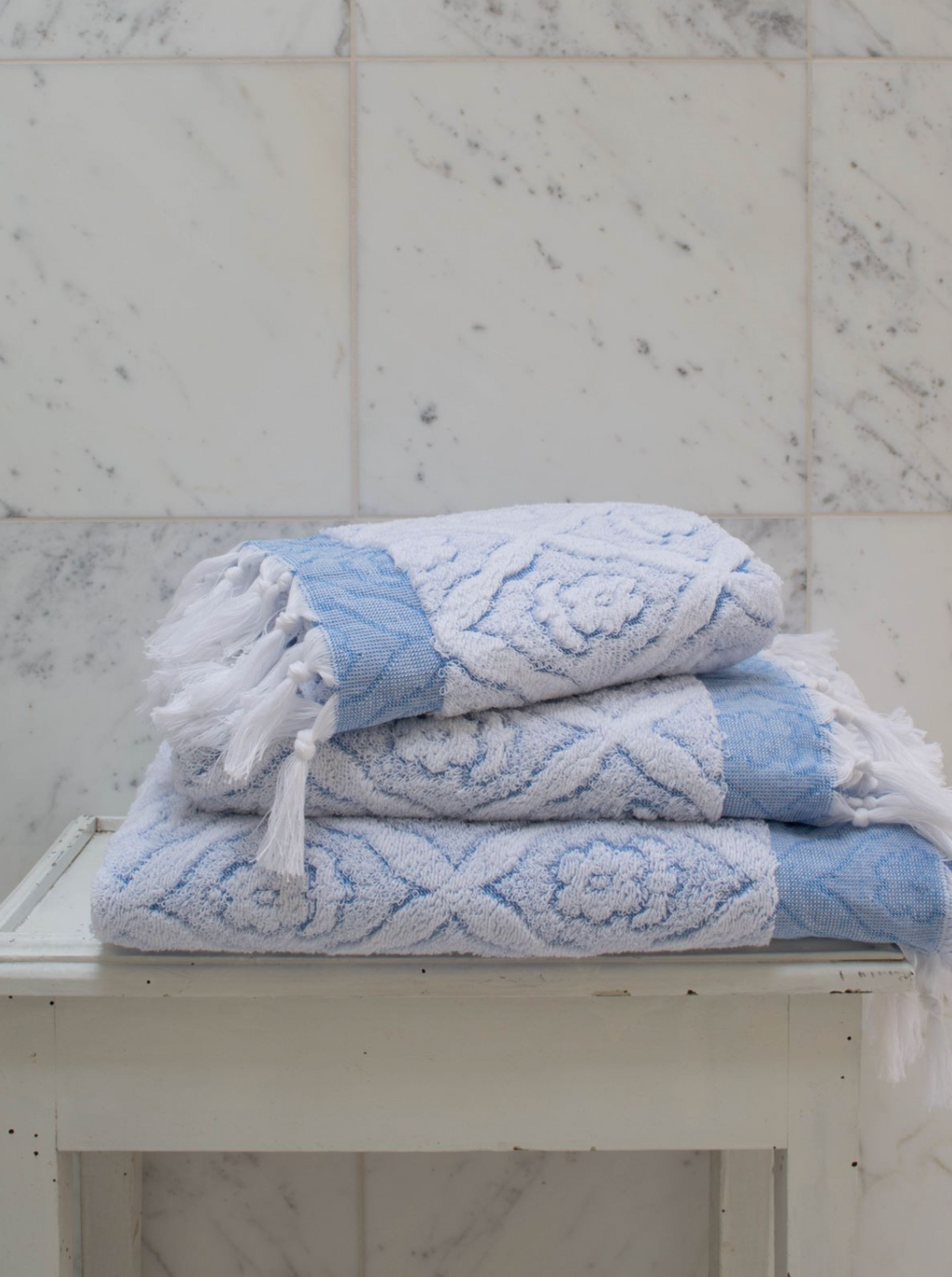 Blue DORA hand towel measuring 100x50 cm, displayed folded with soft textured fabric and subtle woven pattern.