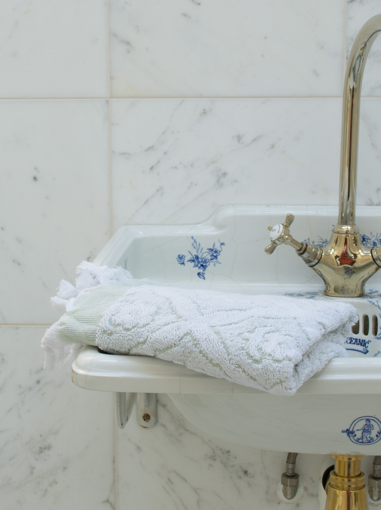 Green DORA hand towel, 100x50 cm, soft cotton fabric displayed folded on a clean surface.